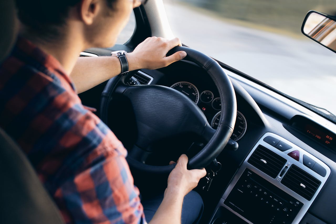 Avaleht Close-up view of a man driving a modern car, showing dashboard and steering details.